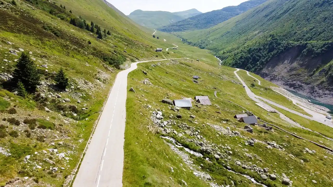caminos sobre montañas, rodeada de arboles, rocas y zonas verdes.