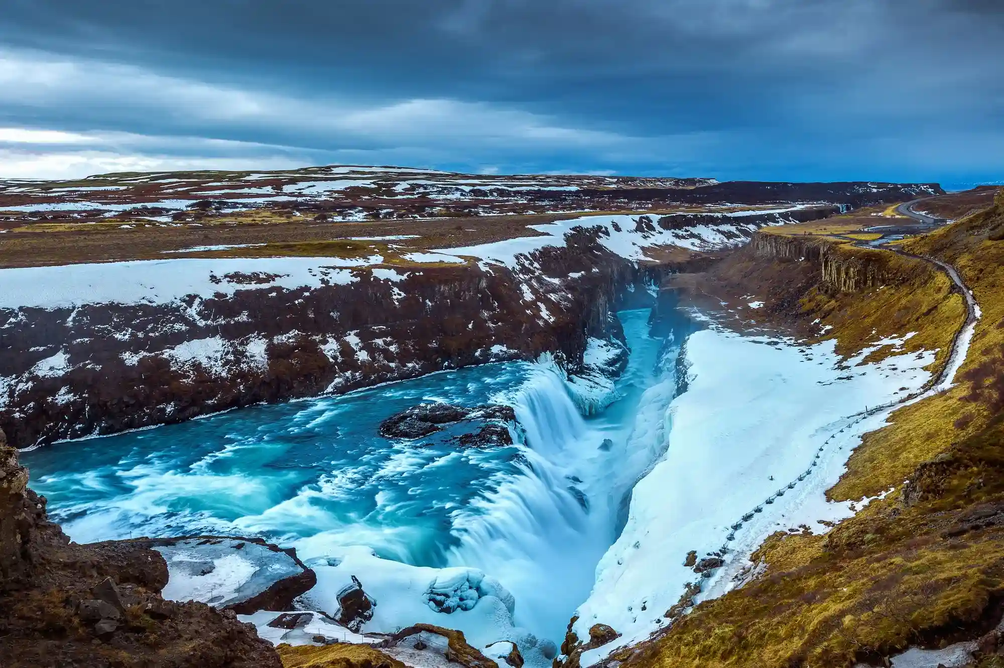 montañas rocosas cubiertas de nieve y zona verde, con una cascada de agua cristalinas.