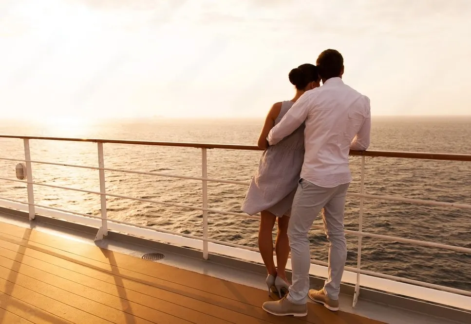 pareja abrazados en crucero mirando el mar en el atardecer.