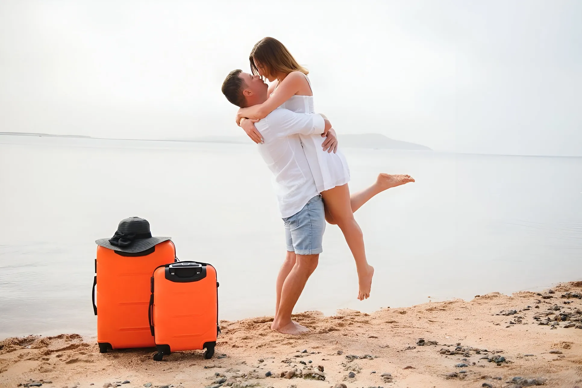 dos personas en el mar y al lado dos maletas de color naranja, un lugar para disfrutar en pareja.