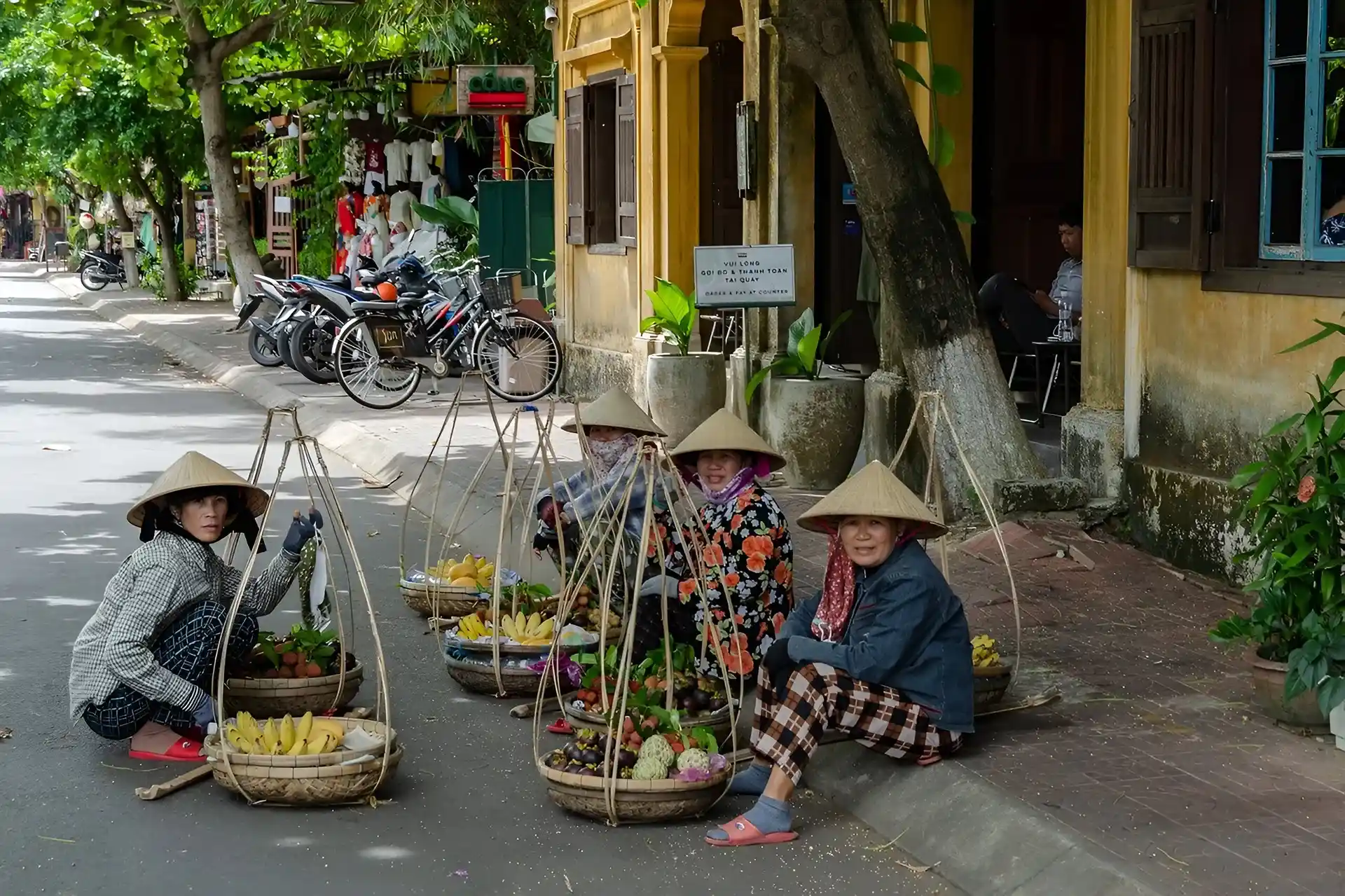 señoras sentadas en el anden de la calle vendiendo frutas en una canasta.