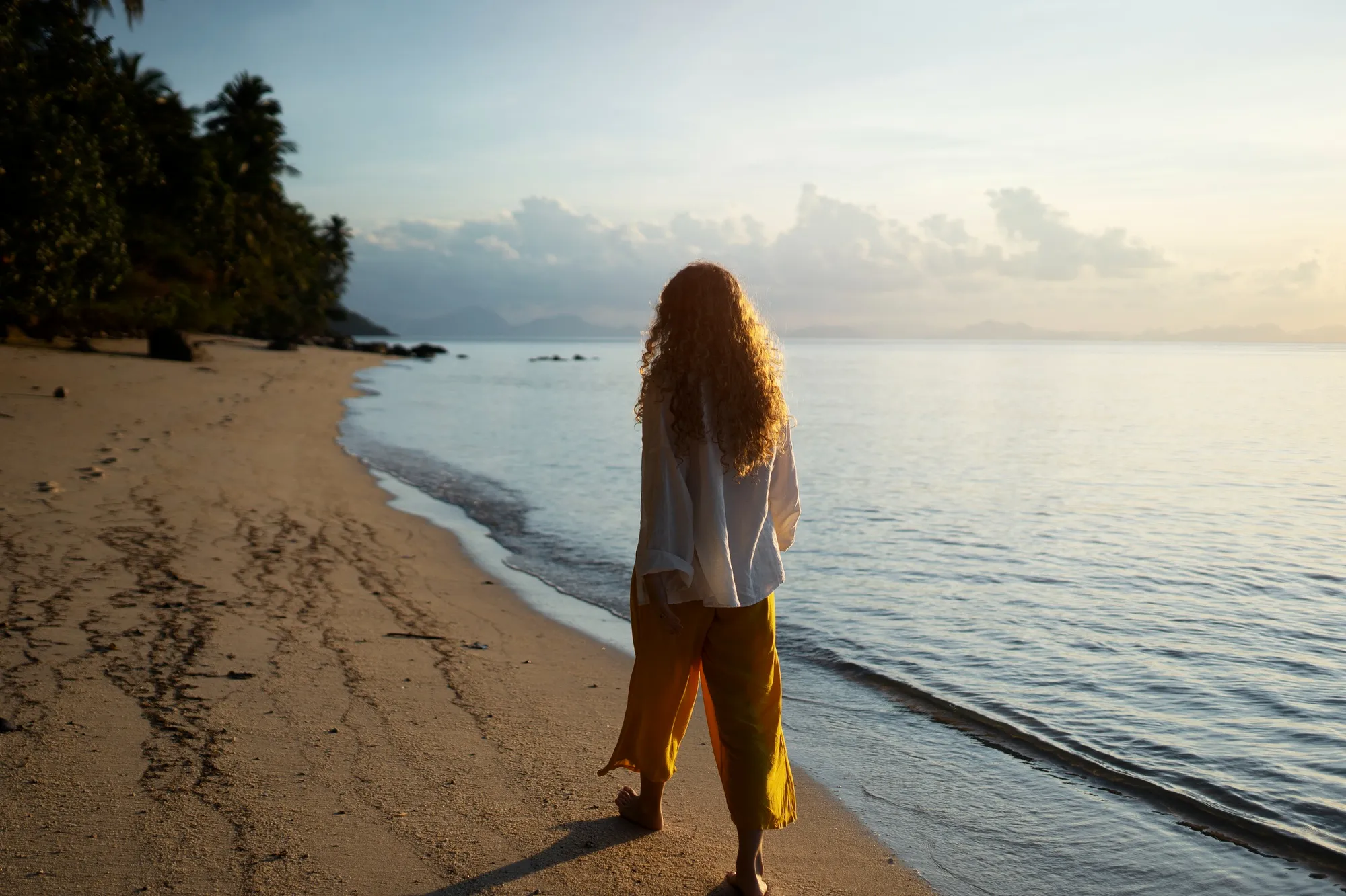 mujer caminando por la playa un lugar tranquilo al atardecer